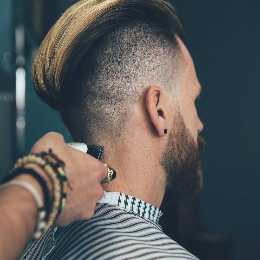 Barber trimming a man's undercut hairstyle.