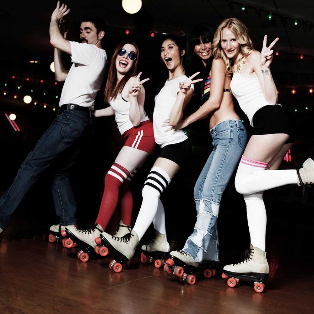 Group of happy young people roller skating indoors.